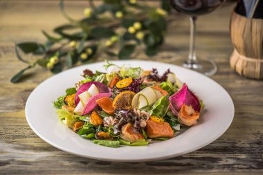 Ahşap masa üzerinde beyaz plaka üzerinde kızarmış tavuk ile sebze salatası