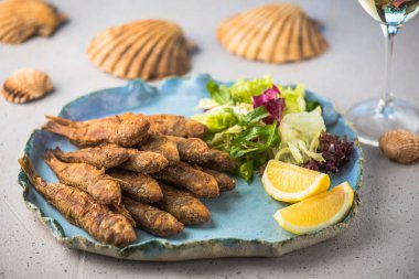 Kızarmış küçük balık tepside limon ve restoran salata ile servis