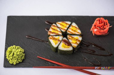 zencefil, wasabi, soya sosu ve gri arka plan üzerinde kayrak gemide yemek çubukları ile lezzetli üçgen suşi