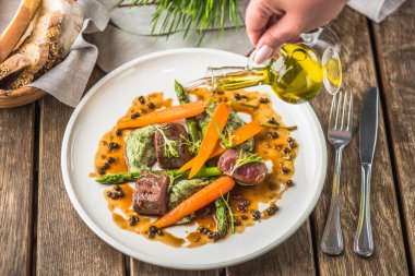 havuç ve sos ile sığır eti üzerine damlama el ahşap masa üzerinde beyaz tabakta servis