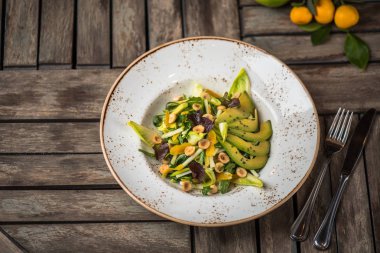 Taze salata avokado ve plaka üzerinde ahşap masa içinde fındık