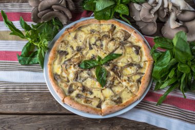 Mantarlı pizza ve ahşap masada fesleğen.