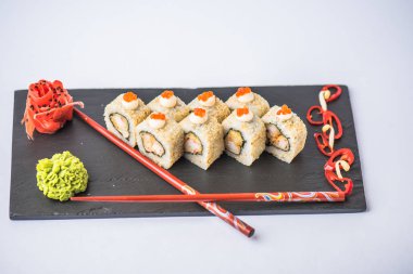 geleneksel Japon suşi rulo wasabi, zencefil ve yemek çubukları ile gri arka plan üzerinde kayrak yönetim kurulu   