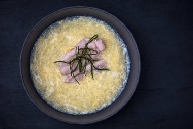 Koyu arka plan üzerinde siyah kase çorbaya oryantal deniz ürünleri