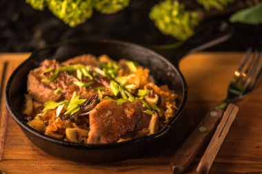 Ahşap tahta üzerinde kızartma tavasında kızarmış tavuk ve sebzeler