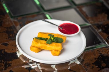 Kızarmış Mozzarella peyniri beyaz tabakta reçel ile sopa.