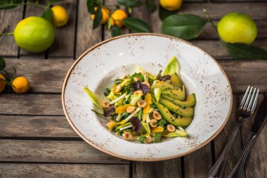 Taze salata avokado ve plaka üzerinde ahşap masa içinde fındık