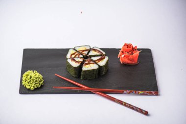 zencefil, wasabi ve gri arka plan üzerinde kayrak gemide yemek çubukları ile lezzetli üçgen suşi