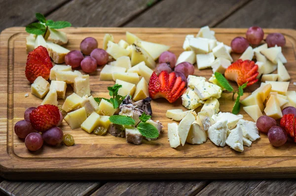 appetizer wooden board with assortment of cheese and berries