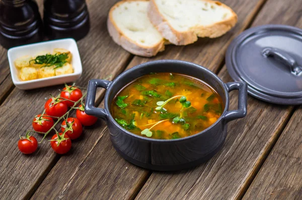 Boiled soup in pan on wooden table with ingredients