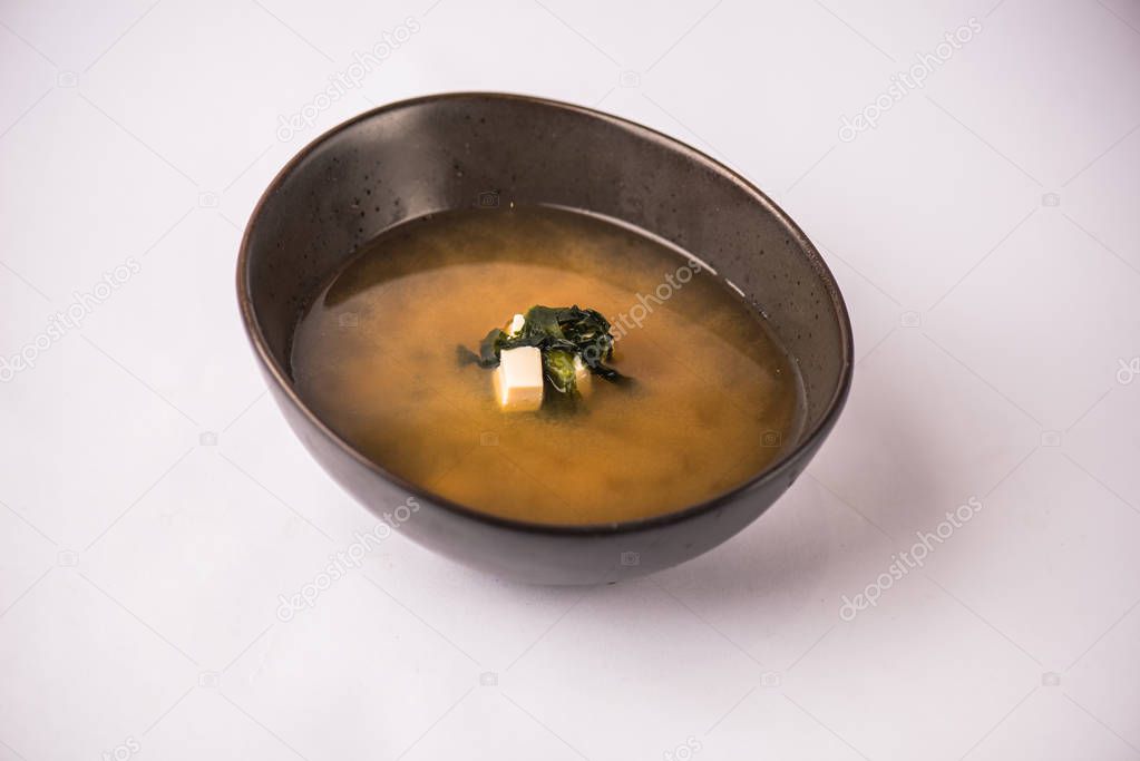 Portion of traditional japanese miso soup in blue bowl on white background