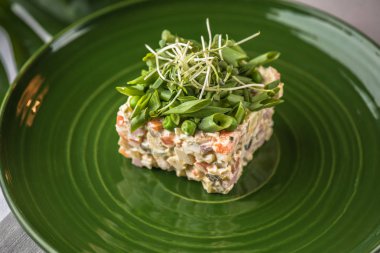 Rus salatası yeşil tabakta yeşillikleri ile süslenmiş