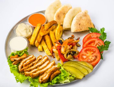 Beyaz arka plan üzerinde metal plaka üzerinde tabak yemek oryantal tarzı - kızarmış eti, ızgara biber, pide, domates, salatalık, patates, Humus, soslar