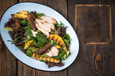 Taze sebze salata tavuk ve ahşap masa üzerinde plaka üzerinde ızgara mango ile