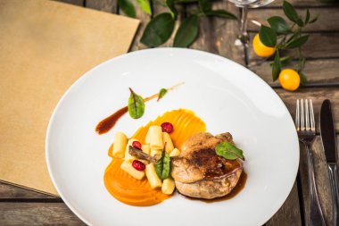 Ahşap masa üzerinde beyaz tabakta ördek bacak garnitür ile servis