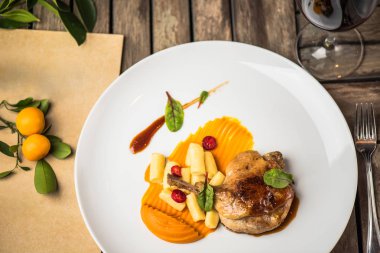 Ahşap masa üzerinde beyaz tabakta ördek bacak garnitür ile servis