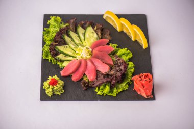Beyaz arka plan üzerinde tabakta taze ton balıklı sashimi sebze ile servis