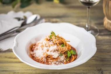 Ahşap masa üzerinde beyaz tabakta servis domates soslu makarna çeşitleri