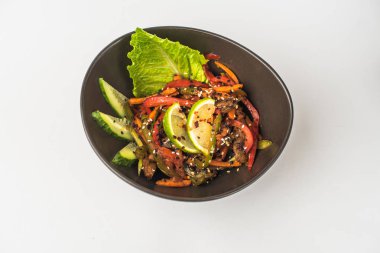 Beyaz arka planda Asya kızartılmış sebzeler ve et kase