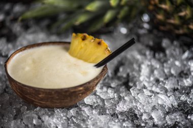 Hindistan cevizi sütü ve buz ile koyu arka plan bardakta ananas kokteyli