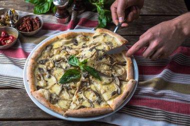 insan eli parça pizza mantar ve fesleğen ahşap masanın üzerine alarak