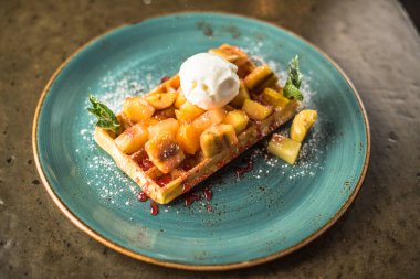 Mavi tabakta tatlı waffle, muz ve top vanilyalı dondurma ile