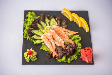 Beyaz arka plan üzerinde tabakta taze karides sashimi sebze ile servis