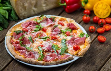 et, roka, parmesan ve kiraz domates ile güzel pişmiş pizza ahşap masa üzerinde görmek