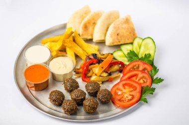 Tabak vejetaryen yemek oryantal tarzı: falafel, ızgara biber, pide, domates, salatalık, patates, Humus, beyaz zemin üzerine metal tabakta soslar