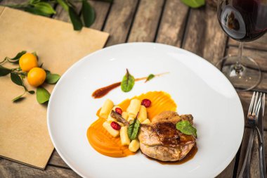 Ahşap masa üzerinde beyaz tabakta ördek bacak garnitür ile servis