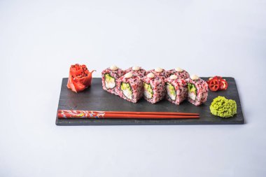 gurme suşi yakından görmek gri arka plan üzerinde kayrak gemide yemek çubukları, zencefil ve wasabi ile rulo 