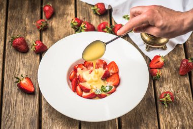 insan eli yağan taze çilek süt ile plaka üzerinde ahşap masaya jam