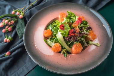 Deniz ürünleri meze taze yeşillikleri ile koyu kumaş tabakta servis 