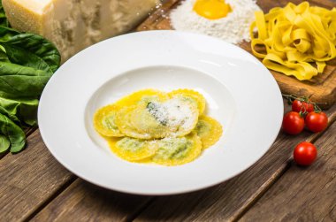 Geleneksel İtalyan ıspanak Mantı malzemelerle ahşap masa üzerinde beyaz tabakta servis