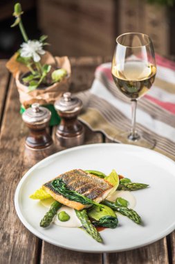 Balık fileto ahşap masa üzerinde beyaz tabakta servis yeşil kuşkonmaz ile kavrulmuş