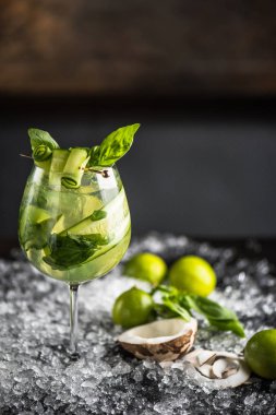 Fesleğen, limon ve cam buz ile koyu arka plan üzerine Hindistan cevizi ile kokteyl