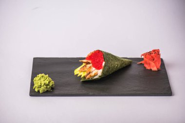 gurme suşi koni havyar, avokado, wasabi ve zencefil ile gri arka plan üzerinde kayrak gemide görmek