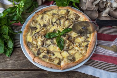 Mantarlı pizza ve ahşap masada fesleğen.