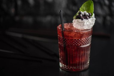 Yaprak ve koyu arka plan üzerinde yaban mersini taze kokteyl cam süslenmiş