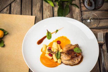 Ahşap masa üzerinde beyaz tabakta ördek bacak garnitür ile servis