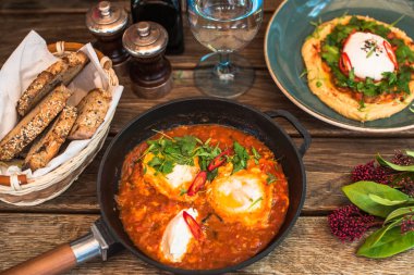 Humus ve rustik ahşap masa ekmek tavada shakshuka