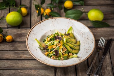 Taze salata avokado ve plaka üzerinde ahşap masa içinde fındık