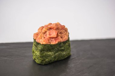 lezzetli geleneksel suşi orkinos ve nori deniz yosunu ile gri arka plan üzerinde kayrak gemide görmek