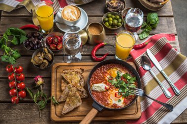 shakshuka, zeytin, biber, domates, ekmek, meyve suyu ve kahve rustik ahşap tablo ile kahvaltı
