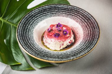 Servis tabağına ve yenilebilir çiçeklerle süslenmiş tatlı krem tatlı