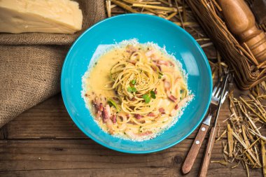 Deniz ürünleri makarna krema soslu ahşap masa mavi tabakta servis