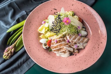 pembe plaka üzerinde ızgara tavuk göğsü ile sebze salatası