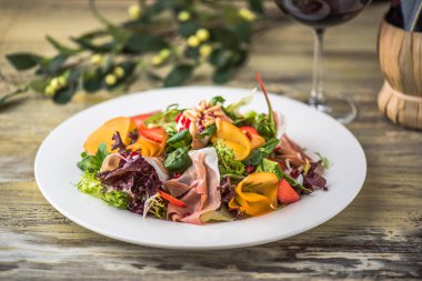 Ahşap masa üzerinde beyaz tabakta sebze salatası jambon ile hizmet