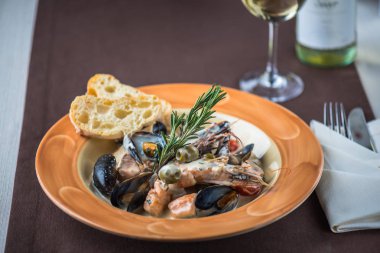 Masa örtüsü ve cam beyaz şarap üzerinde ekmek ile plaka üzerinde deniz ürünleri çanak