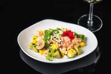 İncelik sebze salatası kadeh beyaz şarap ile siyah arka plan üzerine tabakta servis